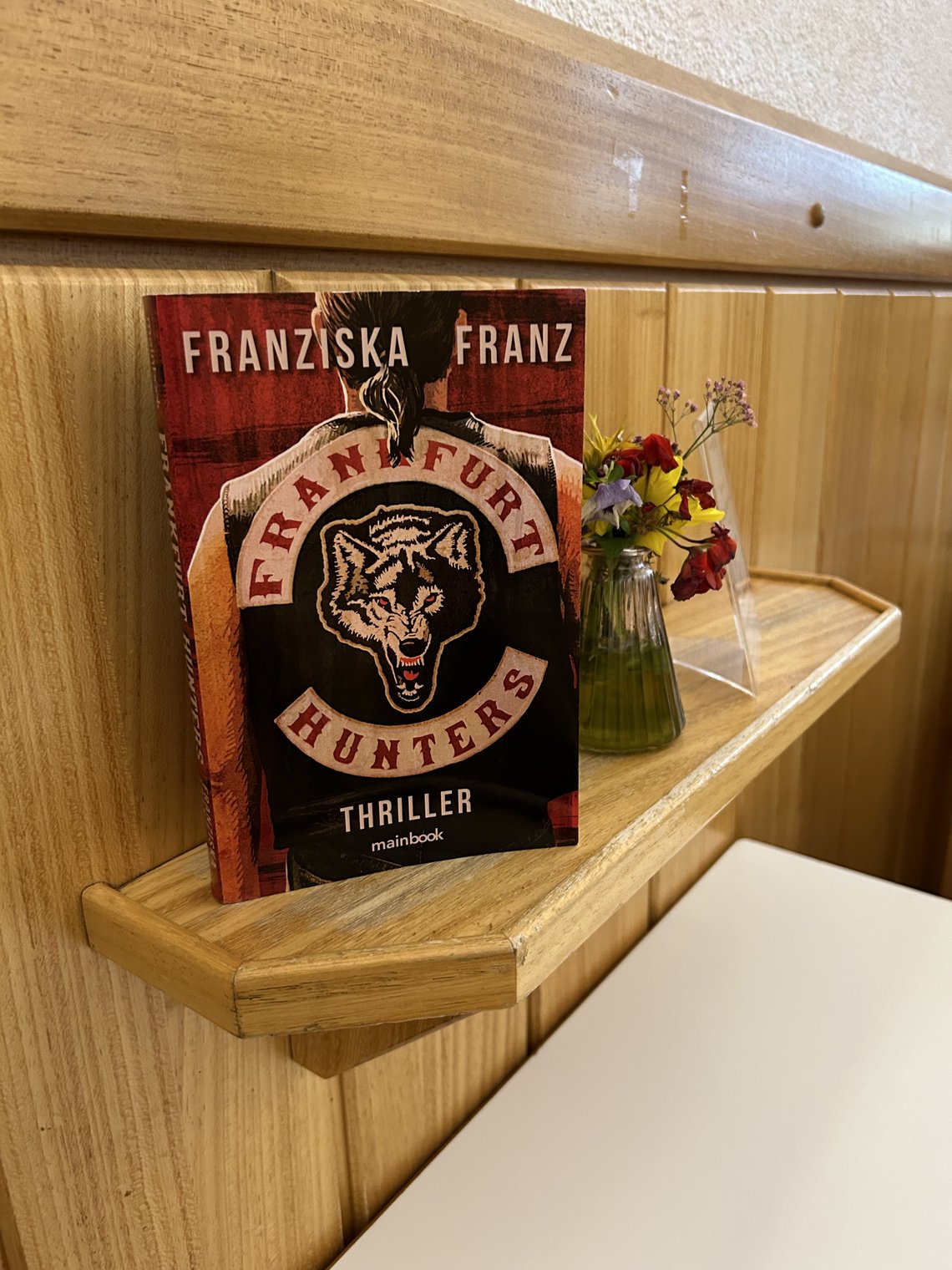 Buch "Frankfurt Hunters" von Franziska Franz steht auf einem der Abstellregale neben einem Tisch im Frühstücksraum des Franziskustreffs